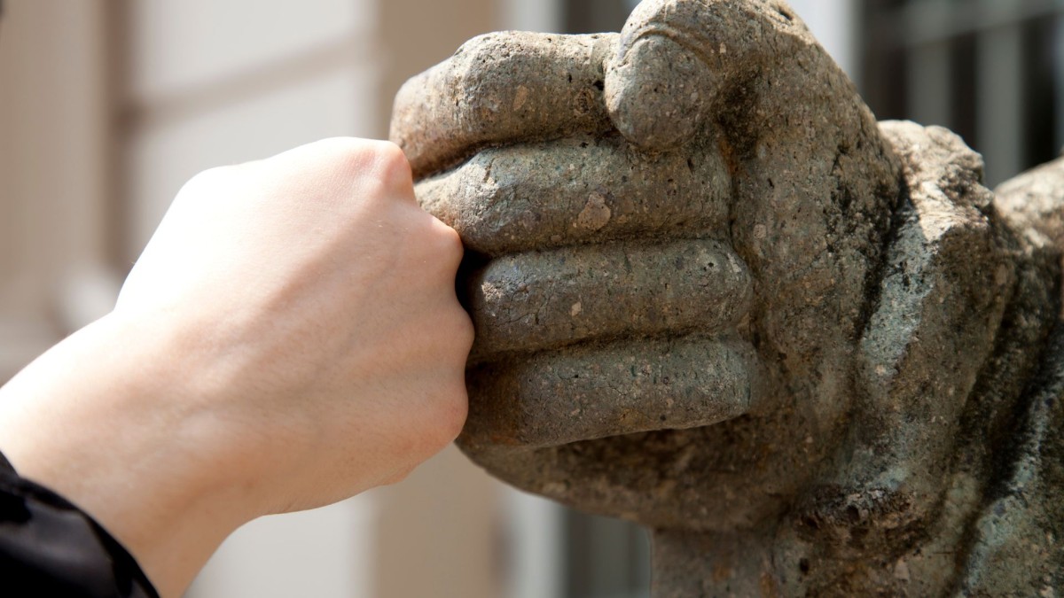 Fist bump zwischen menschlicher Hand und Hand einer Statue